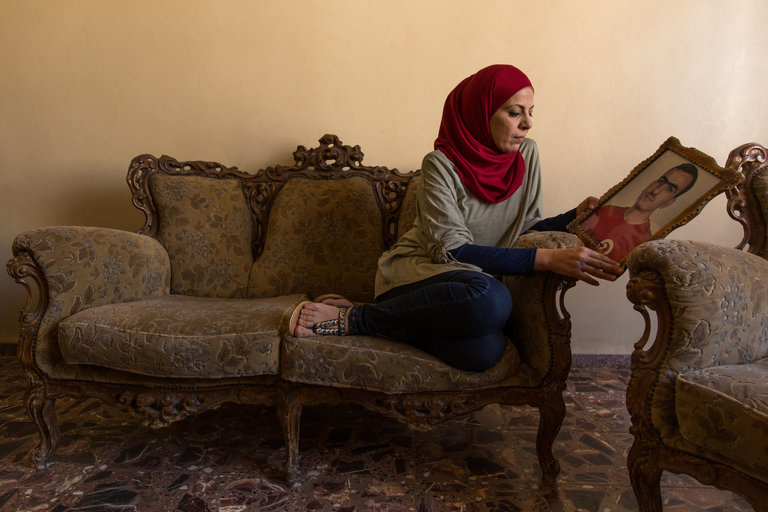 Шифа аль-Квидси держит в руках фотографию брата, Махмуда аль-Квидси, у нее дома в Тулькраме северная часть Западного побережья. (Автор снимка — Рина Кустелнуово, для Нью Йорк Таймс)

